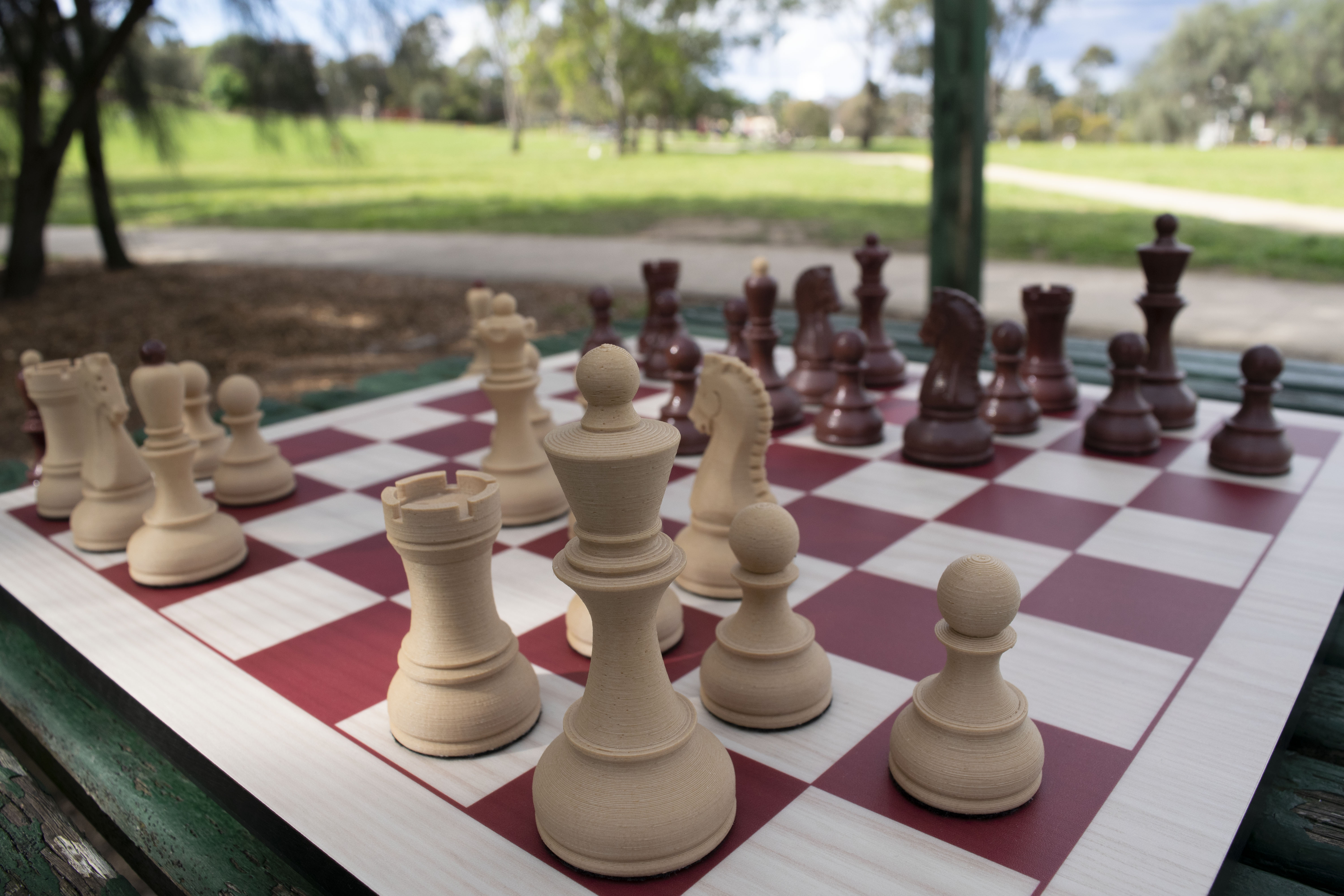 Wood-finish chess pieces on an outdoor chessboard